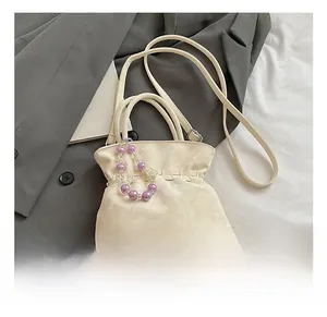 Detailed view of cream pleated drawstring bag with purple gradient bead chain decoration