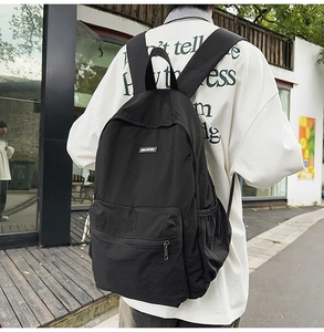 Outdoor shot of a black nylon backpack featuring a brand logo and adjustable straps