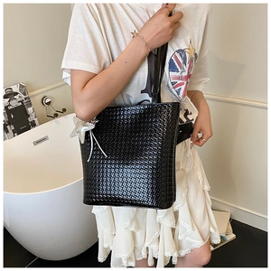 Close-up of black woven texture bucket bag featuring a silver star charm and sleek finish