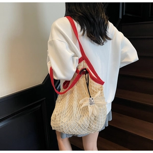 Detail view of large knit mesh tote with red straps and 3D floral charm detail