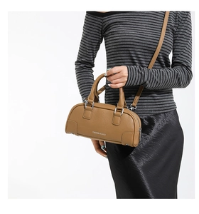 Détail du sac bowling en cuir marron à motif litchi porté par un mannequin