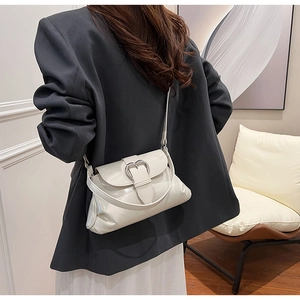 Model view of cream saddle bag with silver heart buckle on a leather shoulder strap