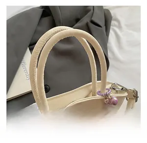 Detail of comfortable braided handle on cream white handbag with purple beaded charm