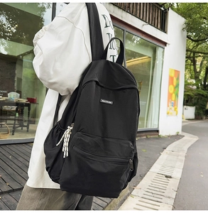 Black lightweight school backpack with Machuge logo and side pocket in urban street setting
