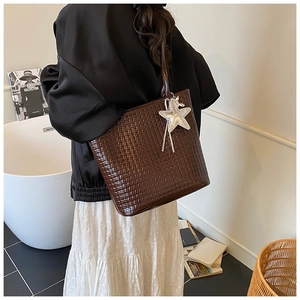 Detail of coffee brown woven texture tote bag with star charm worn on shoulder