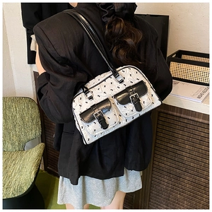 Detail of white shoulder bag with black bow prints and silver buckle pockets on the front