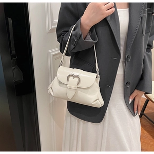 Detail of cream saddle bag with silver heart buckle styled with a blazer and skirt