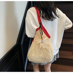 Detail of hollow woven tote bag with red strap and white floral charm for beach style