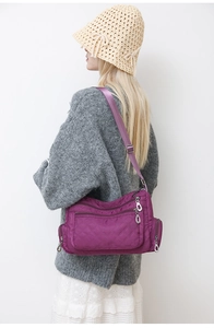Close-up of a purple nylon crossbody bag with quilted diamond pattern and multiple pockets