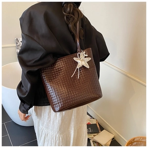 Detail of dark brown woven textured bucket bag with a detachable silver glitter star charm