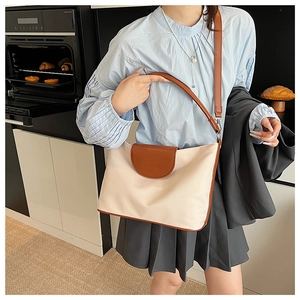 Detail of canvas tote bag with brown leather trim and branded flap in modern setting