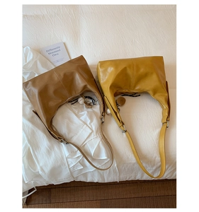 Detail of soft brown and mustard yellow half-moon bags on white fabric background