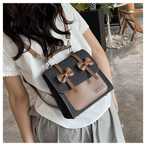 Detail of vintage denim backpack with brown leather bows and stylish metal brand plate