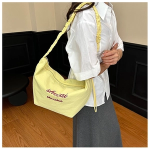 Detail of light yellow pleated shoulder bag with red embroidery on high-quality fabric