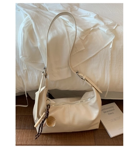 Détail du sac hobo en cuir PU blanc avec fermeture éclair argentée et breloque baseball