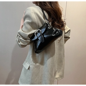 Close-up of black glossy patent leather saddle bag with silver heart-shaped buckle