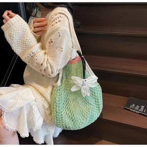 Detail of light green mesh tote bag with 3D white flower charm on wooden stairs