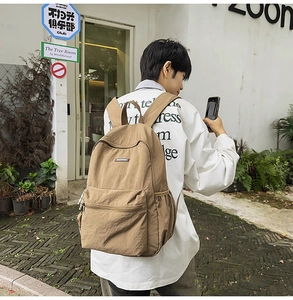 Outdoor lifestyle shot of khaki canvas backpack with front zipper pocket and side pouch