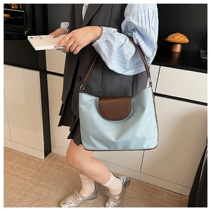 Detail of canvas tote bag with brown leather strap and embossed flip cover in kitchen setting