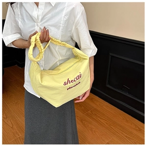 Close-up of a pale yellow pleated croissant bag with cloud-style ruffled shoulder strap