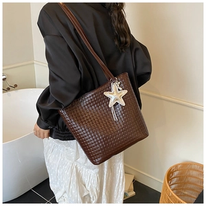 Detail of dark brown woven tote bag with silver starfish charm shown on a model