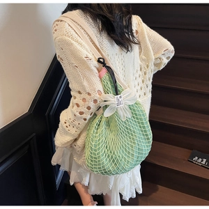 Detail of light green mesh tote bag with a white floral ornament and canvas strap
