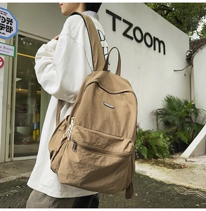 Side view of a casual earth-toned backpack with zipper pockets in a lifestyle street setting