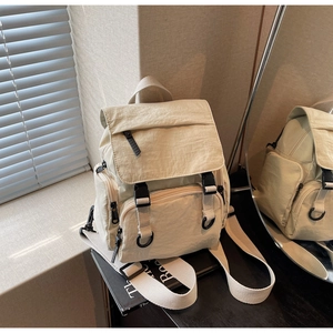 Close-up of beige nylon backpack featuring a flap cover and durable black buckle strap
