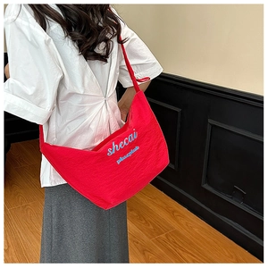 Detail view of large red crossbody bag with blue typography on durable fabric material