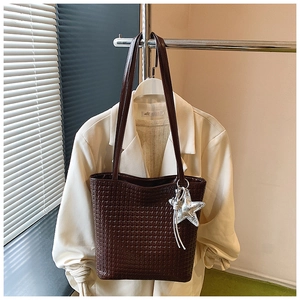 Close-up of woven leather texture on large brown bucket bag with star pendant