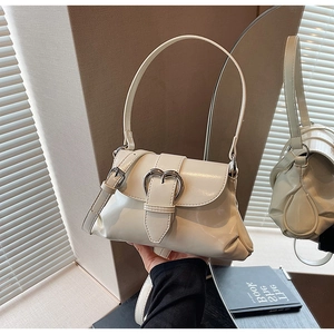 Close-up of cream saddle bag with silver heart buckle and adjustable strap