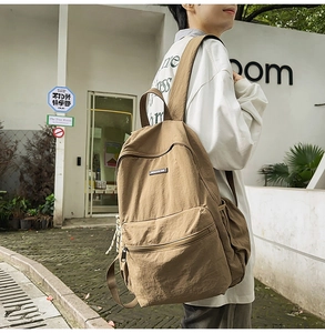 Detail view of large coffee brown canvas backpack with adjustable straps on male model