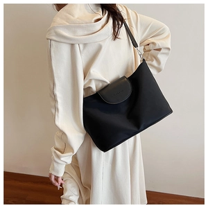 Detail view of the black tote bag with premium leather patchwork and letter embossing