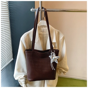 Close-up of deep brown woven texture tote bag with silver star charm and double handles
