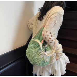 Detail of light green mesh knit tote bag with pink drawstring pouch and daisy charm