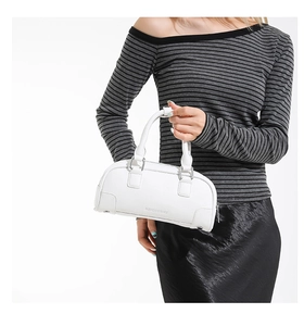 Détail d'un sac Boston blanc en cuir grainé avec fermeture éclair argentée et doubles anses
