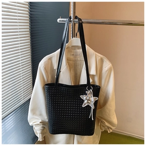 Detail of black woven bucket bag with elegant matte finish and silver star pendant