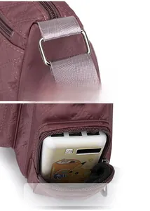 Detail of nylon crossbody bag showing metal strap connector and side zip pocket for power bank