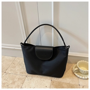 Detail view of the black contrast tote bag with premium leather flap and engraved logo