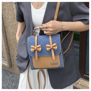 Detailed shot of retro denim and brown leather mini backpack with bow accents for women