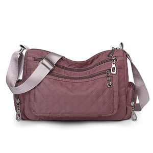 Detailed view of the purple quilted nylon crossbody bag featuring multiple functional zippers