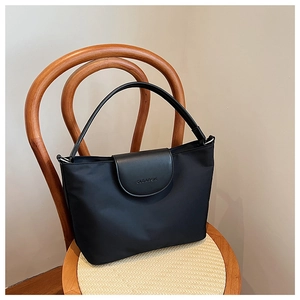 Close-up of the black tote bag with leather flap and embossed OLBARON logo detail