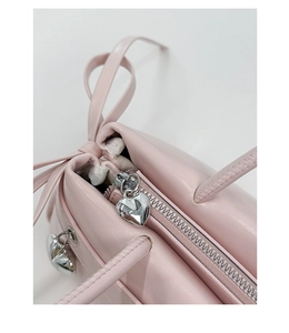 Macro shot of pink leather handbag zipper featuring two silver heart-shaped metal pendants