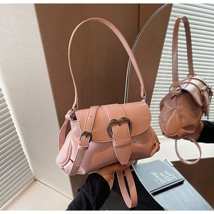 Gros plan sur un sac selle en cuir verni rose avec une boucle argentée en forme de cœur