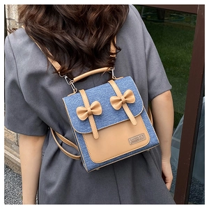 Detail of mini denim and leather backpack featuring decorative brown bows and a top handle