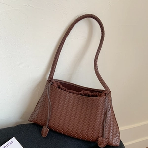 Detailaufnahme der dunkelbraunen geflochtenen Ledertextur einer stilvollen Schultertasche