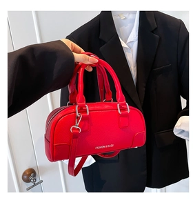 Détail du sac bowling en cuir rouge texturé avec texte blanc et finitions argentées