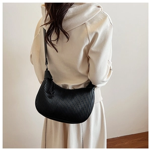 Detail of black pleated half-moon bag texture and shoulder strap on model's shoulder