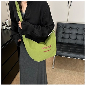 Close-up of grass green crossbody bag with pleated texture and stylish lettering detail