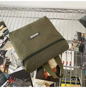 Detailed macro shot of an army green nylon crossbody bag with zipper and logo